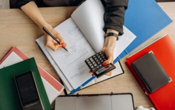 Een ondernemer die aan een bureau werkt en zakelijke facturen en uitgaven beheert, met een calculator en notities.