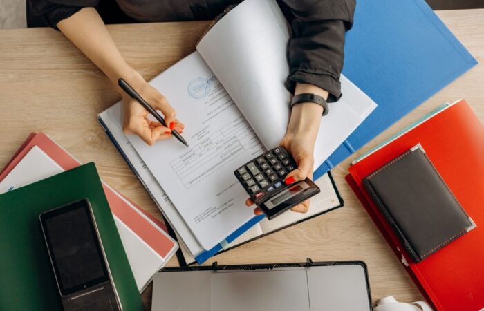 Een ondernemer die aan een bureau werkt en zakelijke facturen en uitgaven beheert, met een calculator en notities.